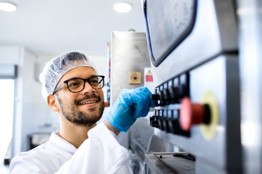Mitarbeiter in Hygienekleidung stellt an einem Bedienfeld Maschinenparameter ein